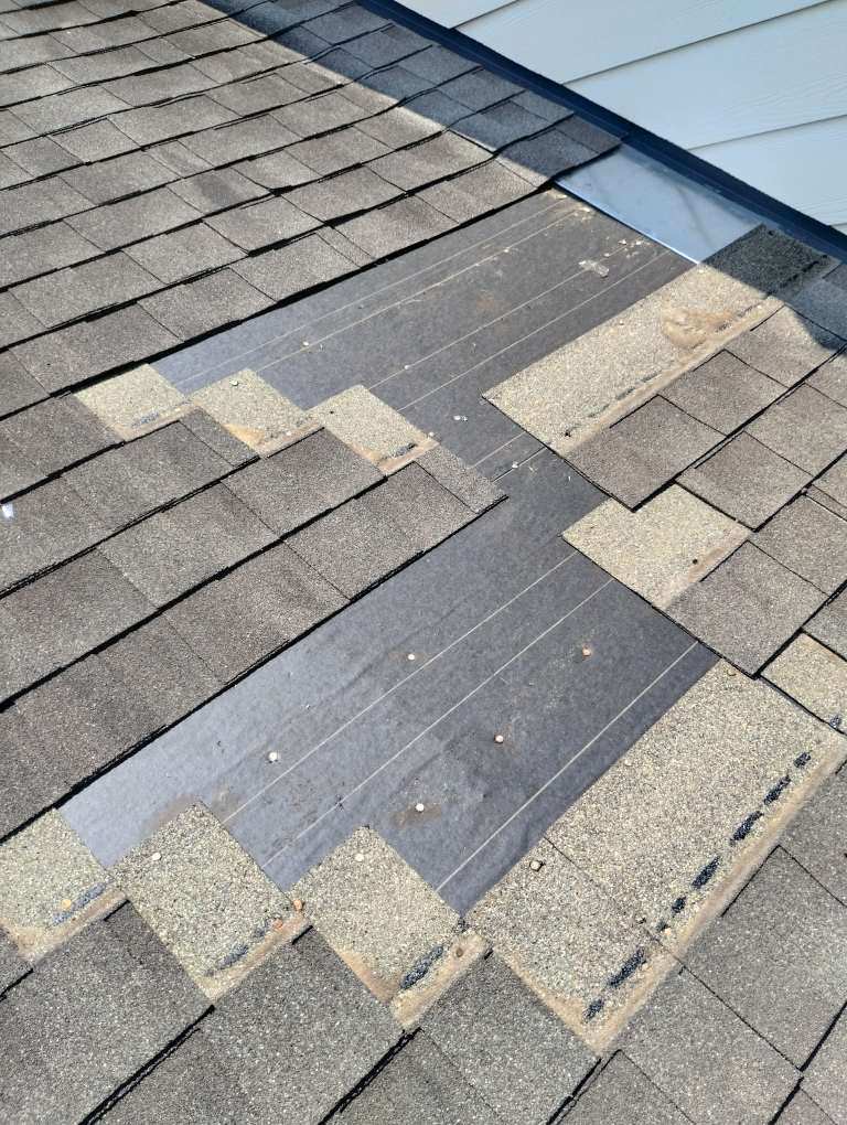 Roof repair and maintenance showing exposed underlayment and missing shingles